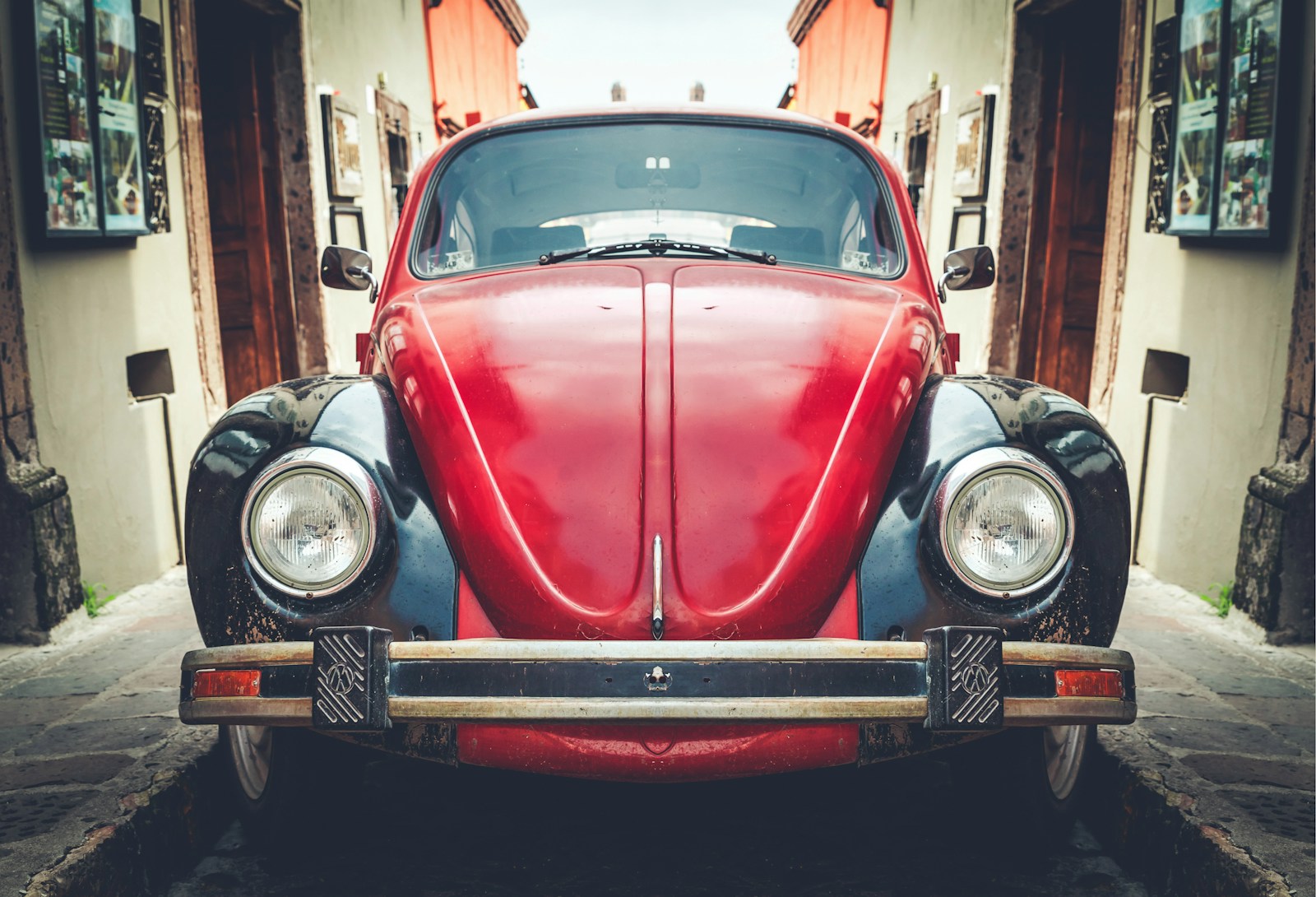 photo of red and black Volkswagen Beetle in alley