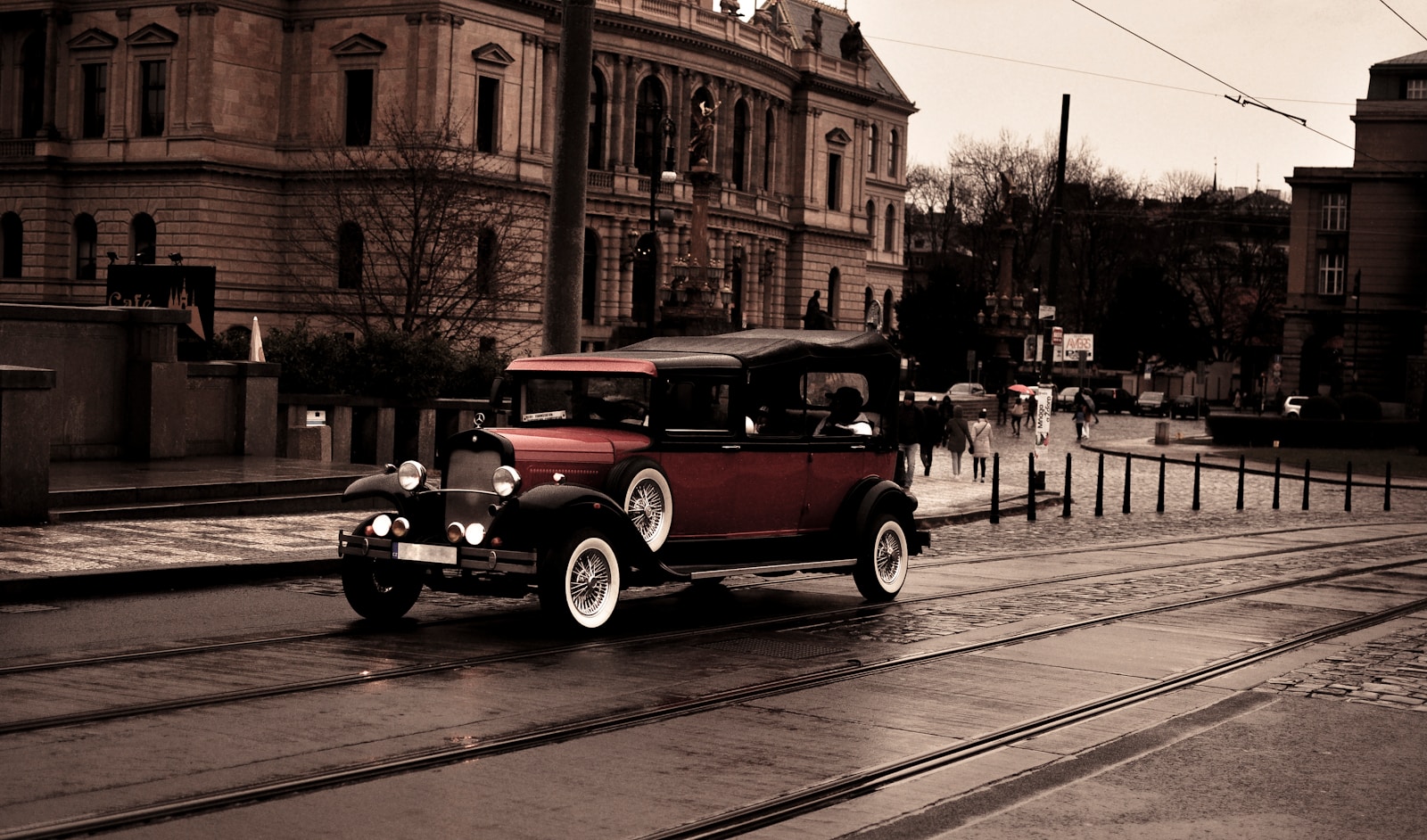 an old fashioned car driving down a wet street